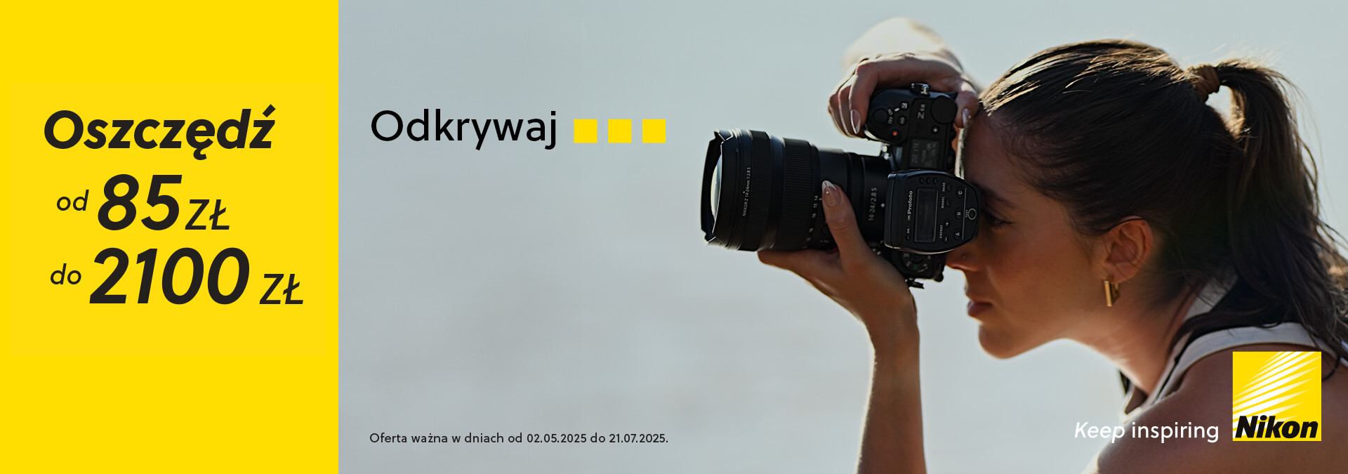 Kobieta z długimi włosami trzyma aparat fotograficzny w dłoniach i robi zdjęcie na zewnątrz